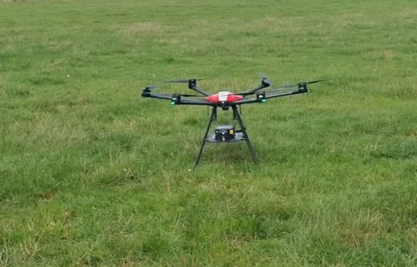 Drone posé sur une pelouse verte, prêt à être utilisé.